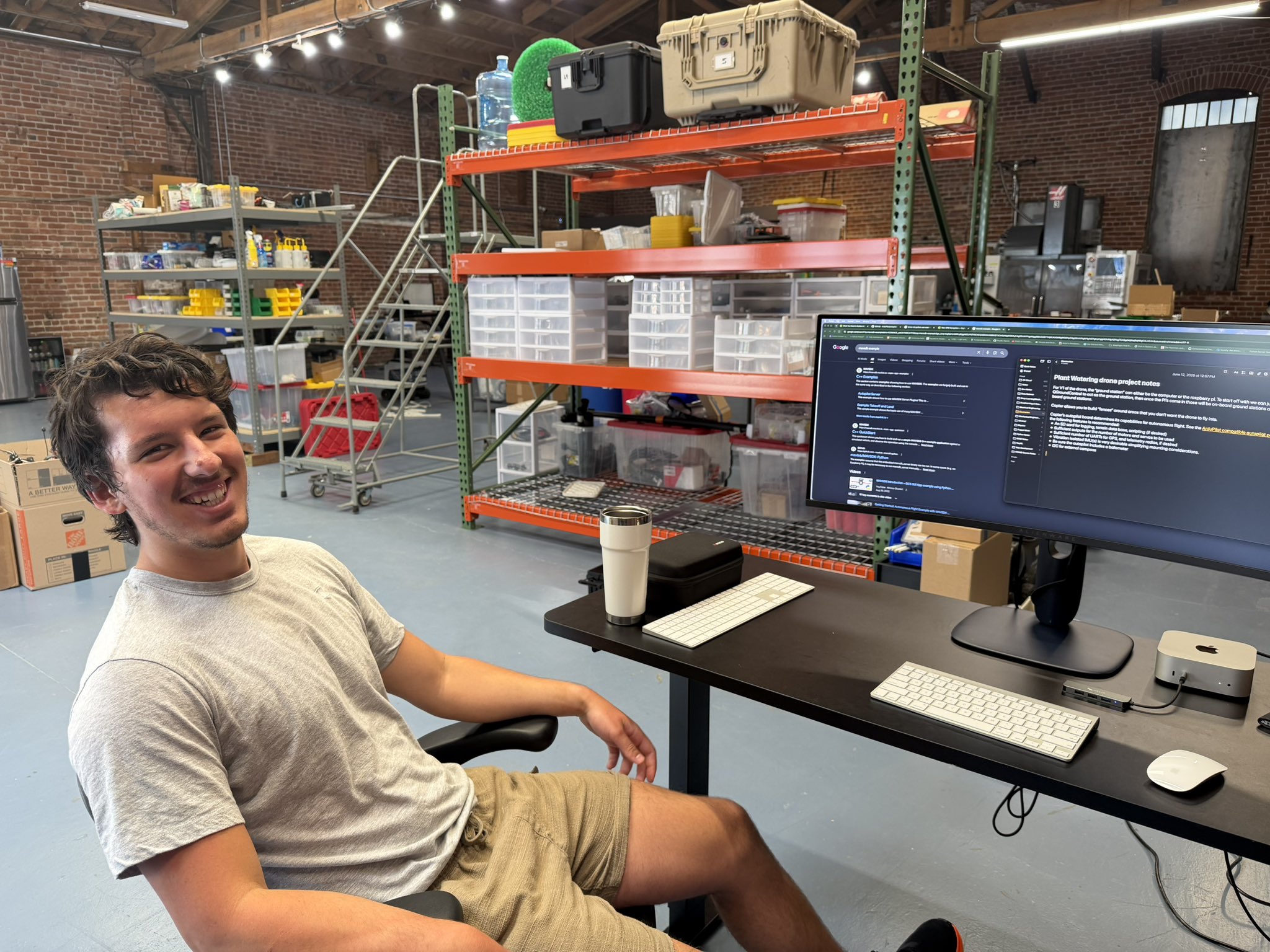 Adam smiling at a desk in an engineering workshop